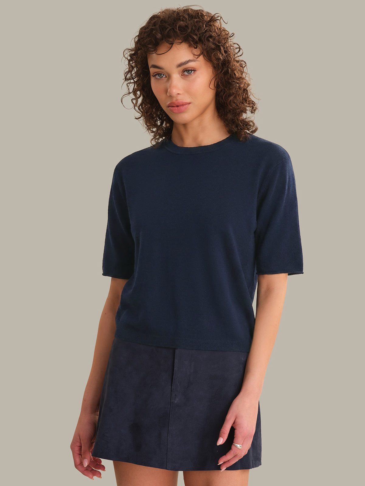 Woman wearing a navy blue outfit against a neutral background
