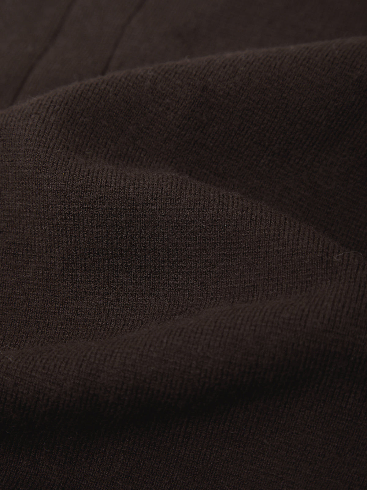 A close-up of dark brown ribbed knit fabric with soft folds and a fine textured weave.