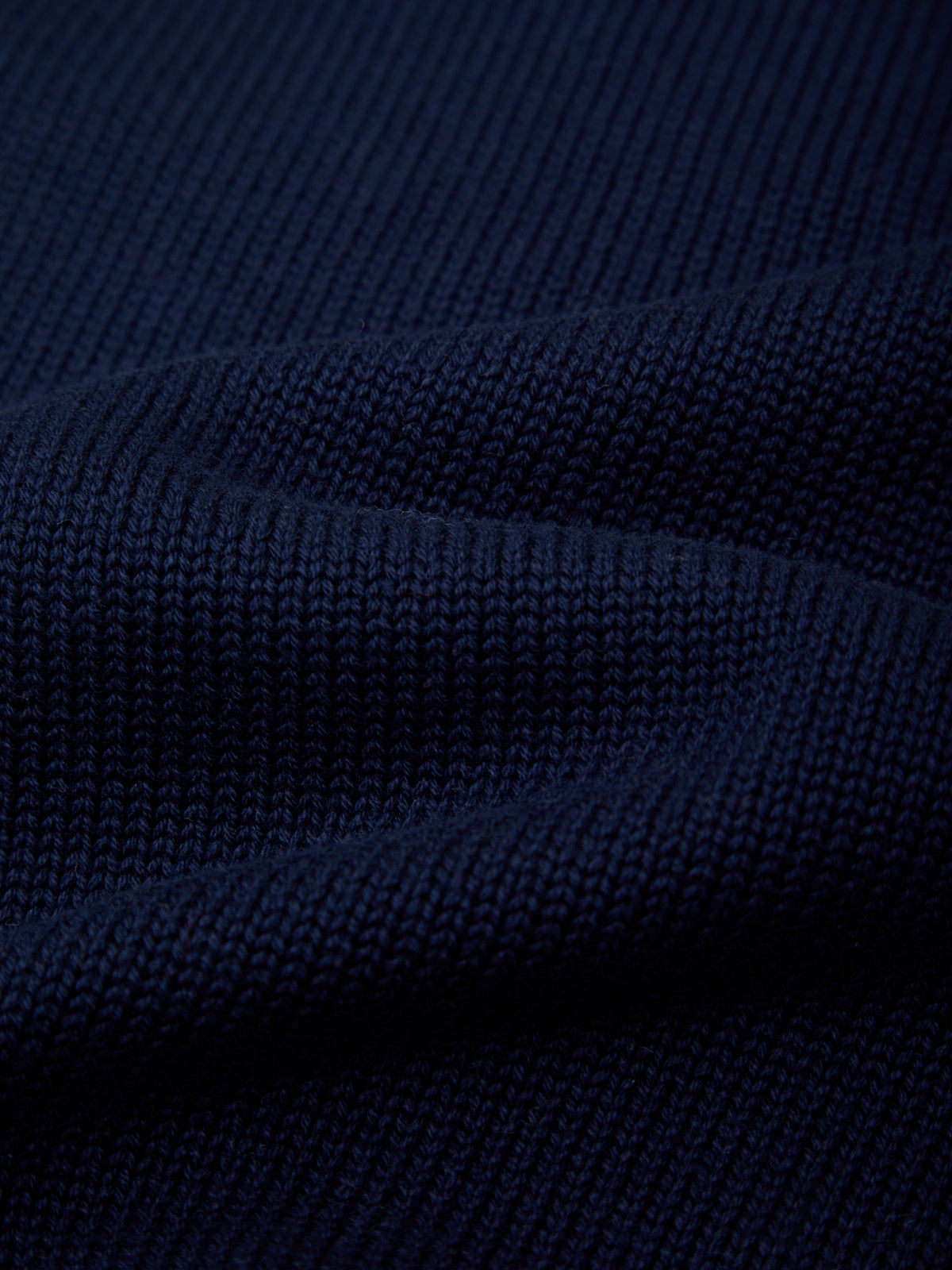 Close-up of dark navy blue ribbed knit fabric with soft folds showing the texture and weave.