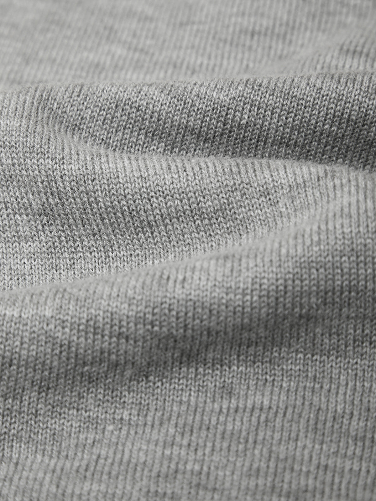 Close-up of a light gray ribbed knit fabric texture with soft folds.