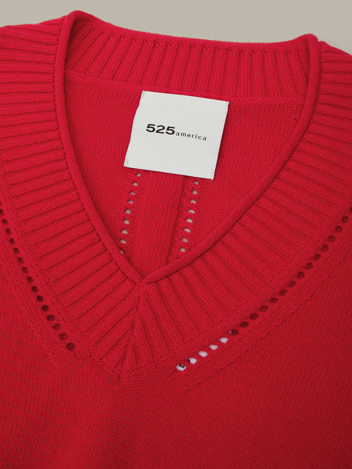 Close-up of a red sweater with a brand label on a beige background