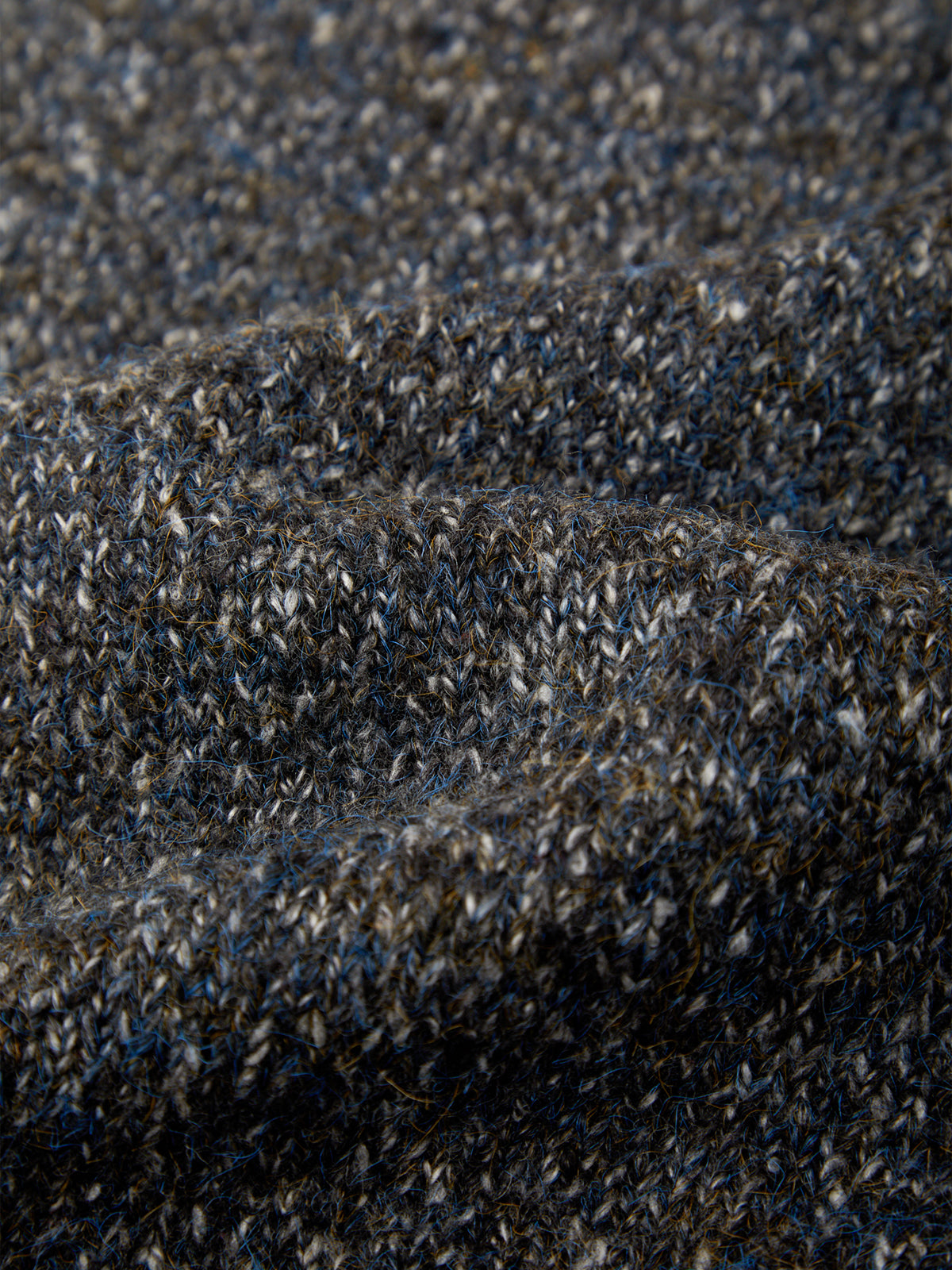 Close-up of a heathered knit fabric with a textured terry-like surface in dark charcoal gray, black, and subtle blue-gray flecks.