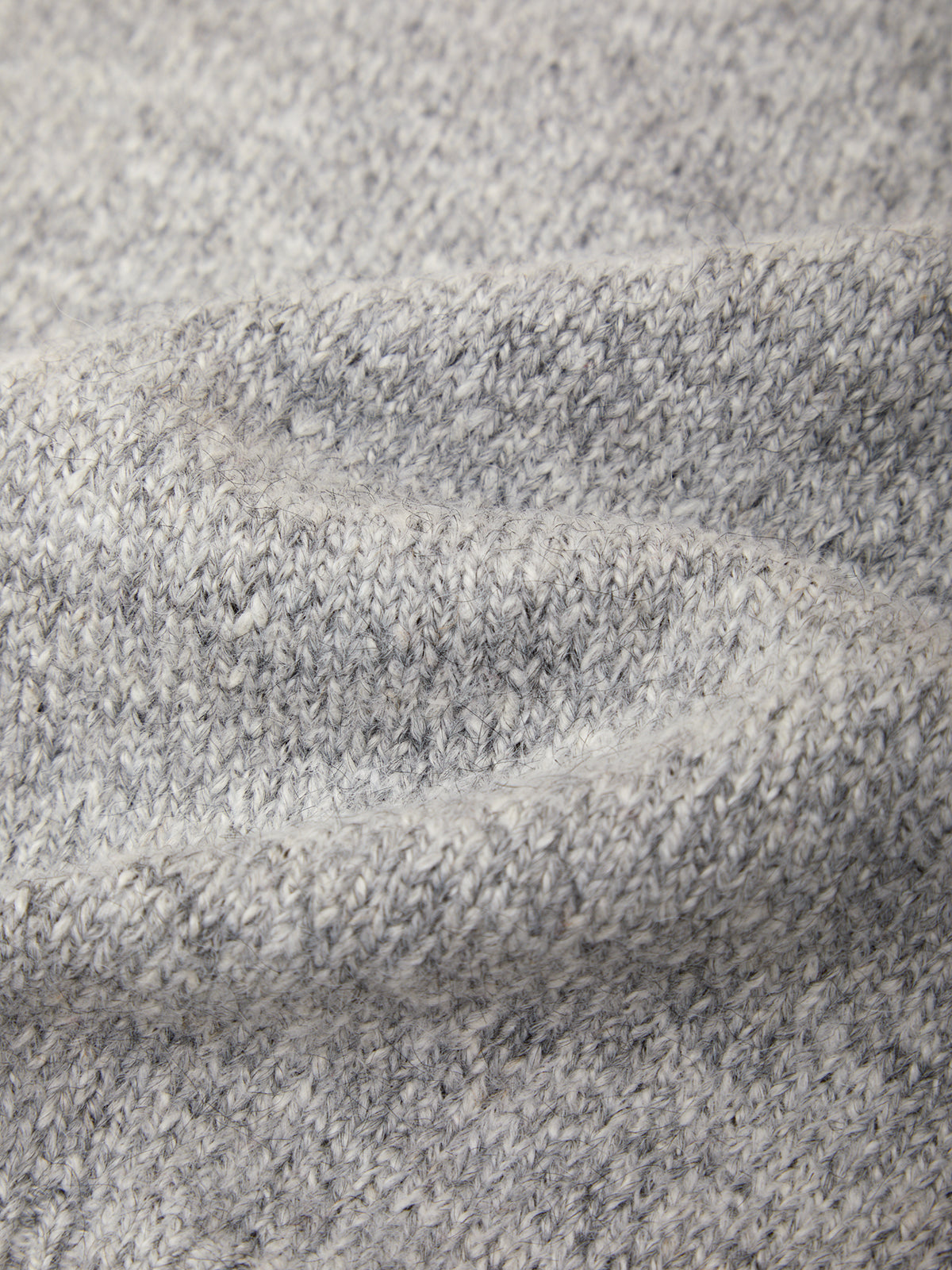 Close-up of a heather gray knit fabric texture with soft folds showing the woven pattern.