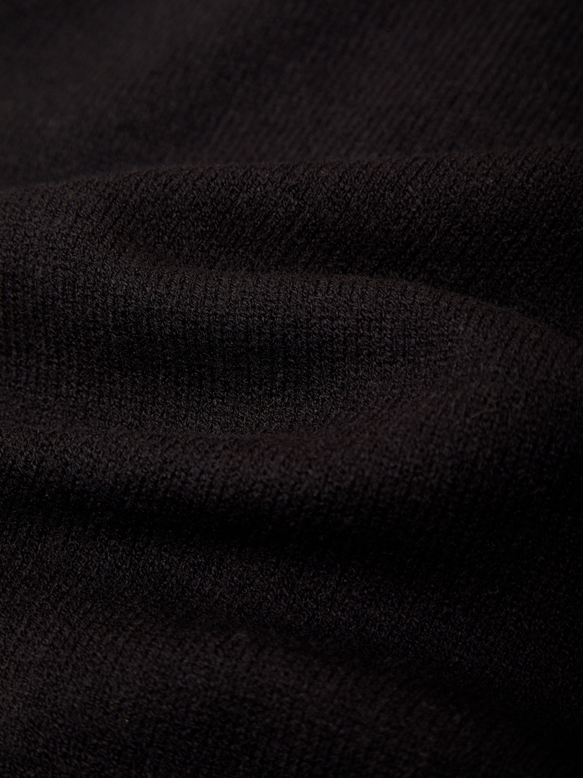 A close-up of dark charcoal gray ribbed knit fabric with soft folds and a fine textured weave.