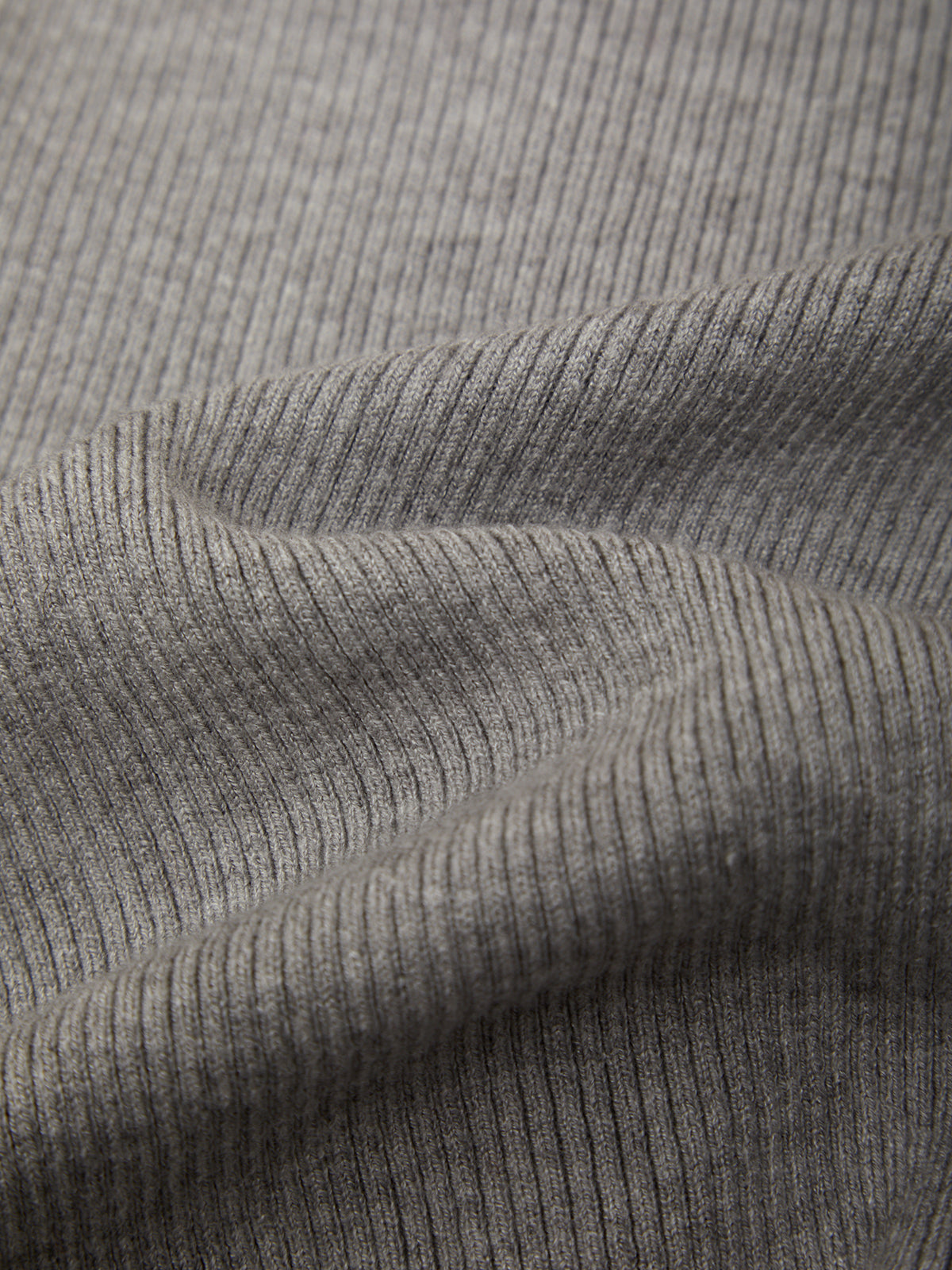 Close-up of a ribbed knit fabric in a heather gray color, showing the texture and folds of the material.