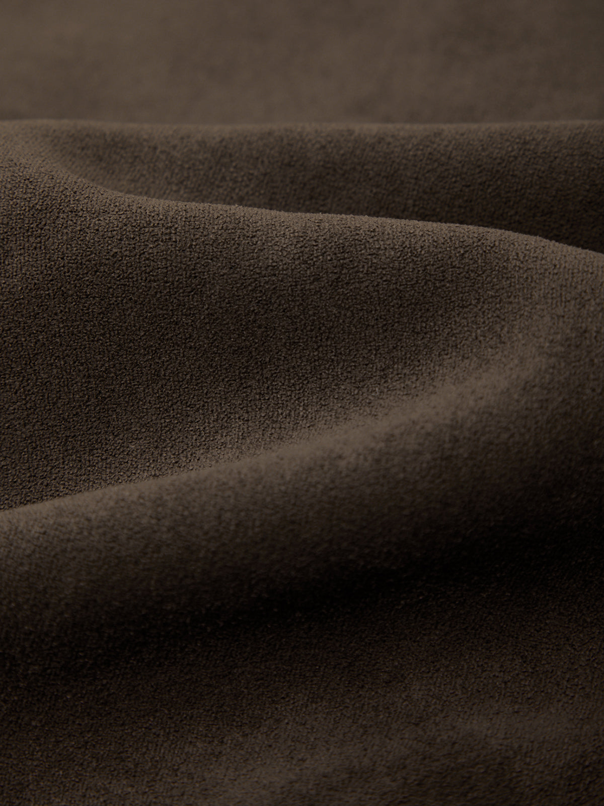 A close-up of draped dark brown textured fabric with soft folds and a matte finish.