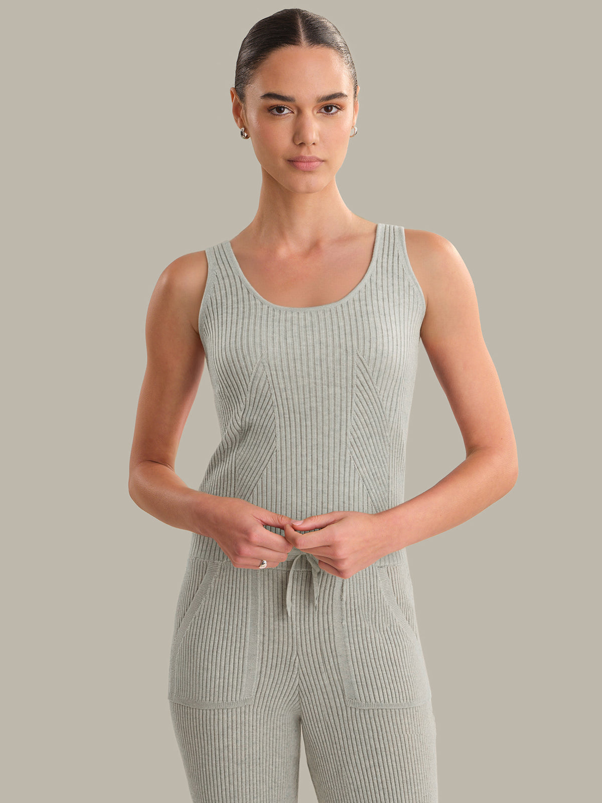 Woman wearing a ribbed knit tank against a plain background