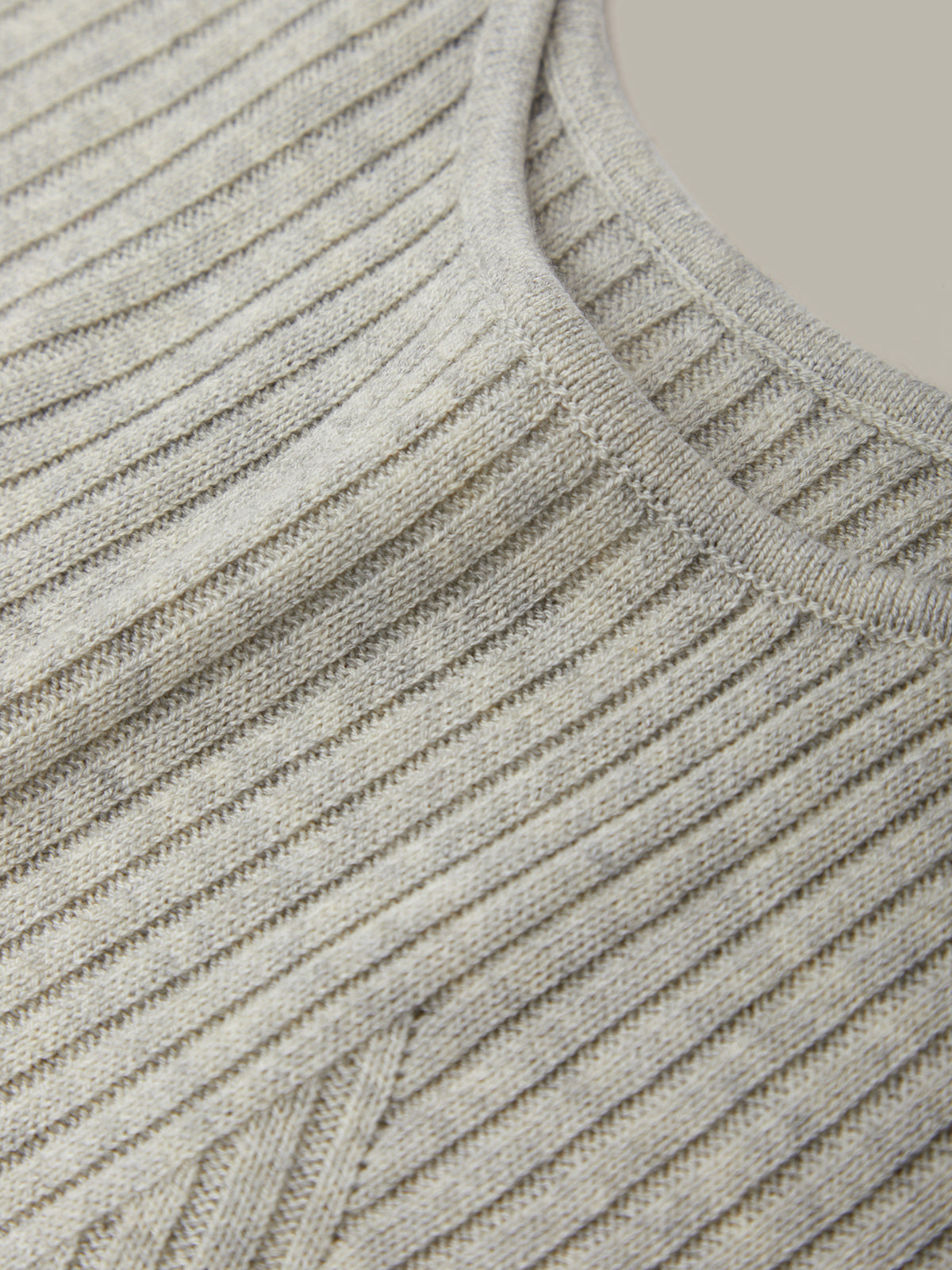 Close-up of a gray ribbed sweater with a neutral background