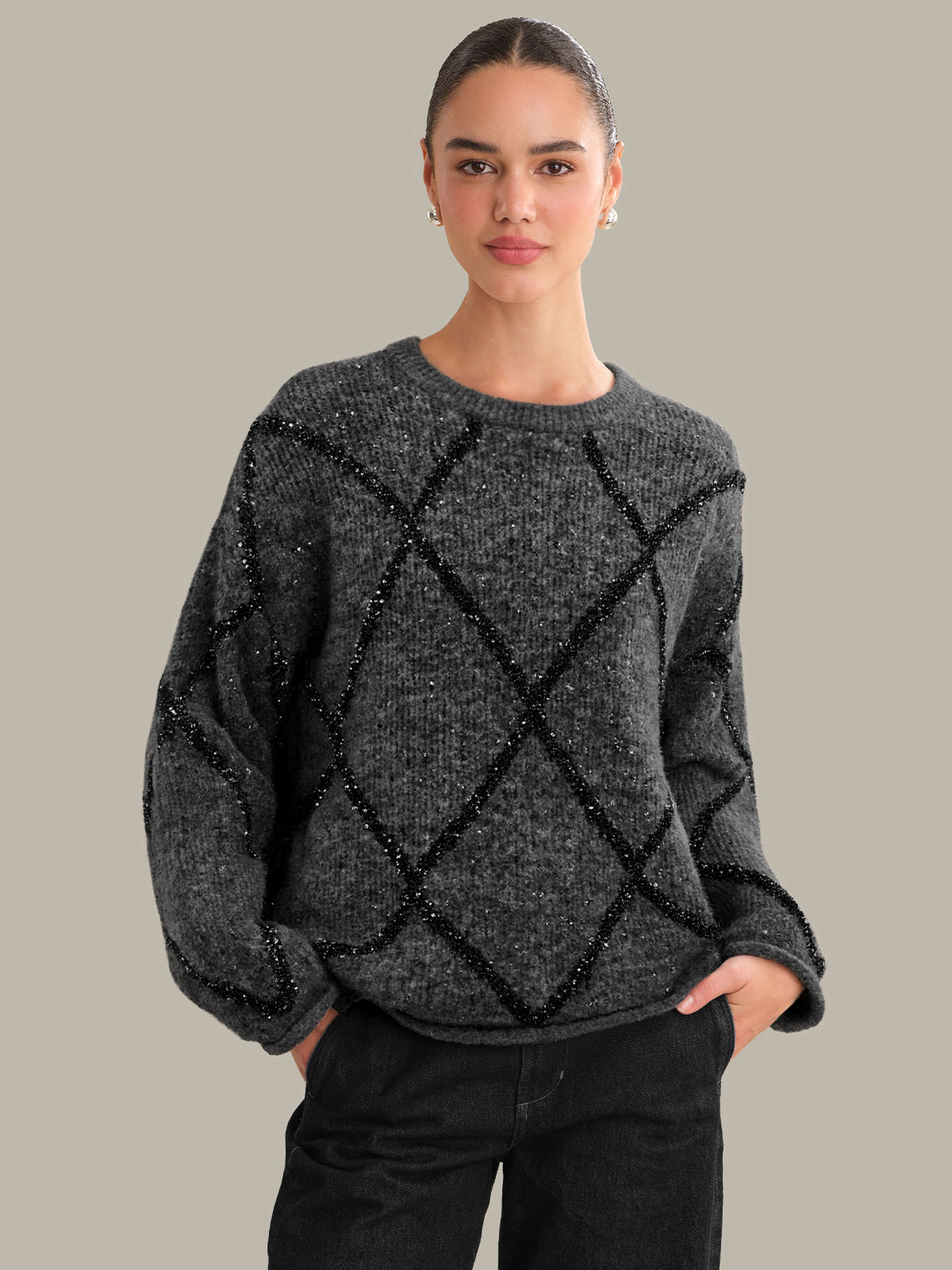 Woman wearing a dark gray sweater with black diamond patterns on a neutral background