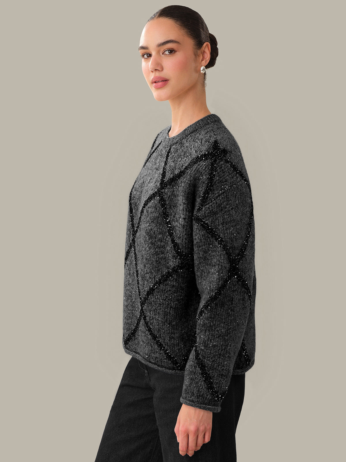 Woman wearing a dark gray textured sweater against a neutral background