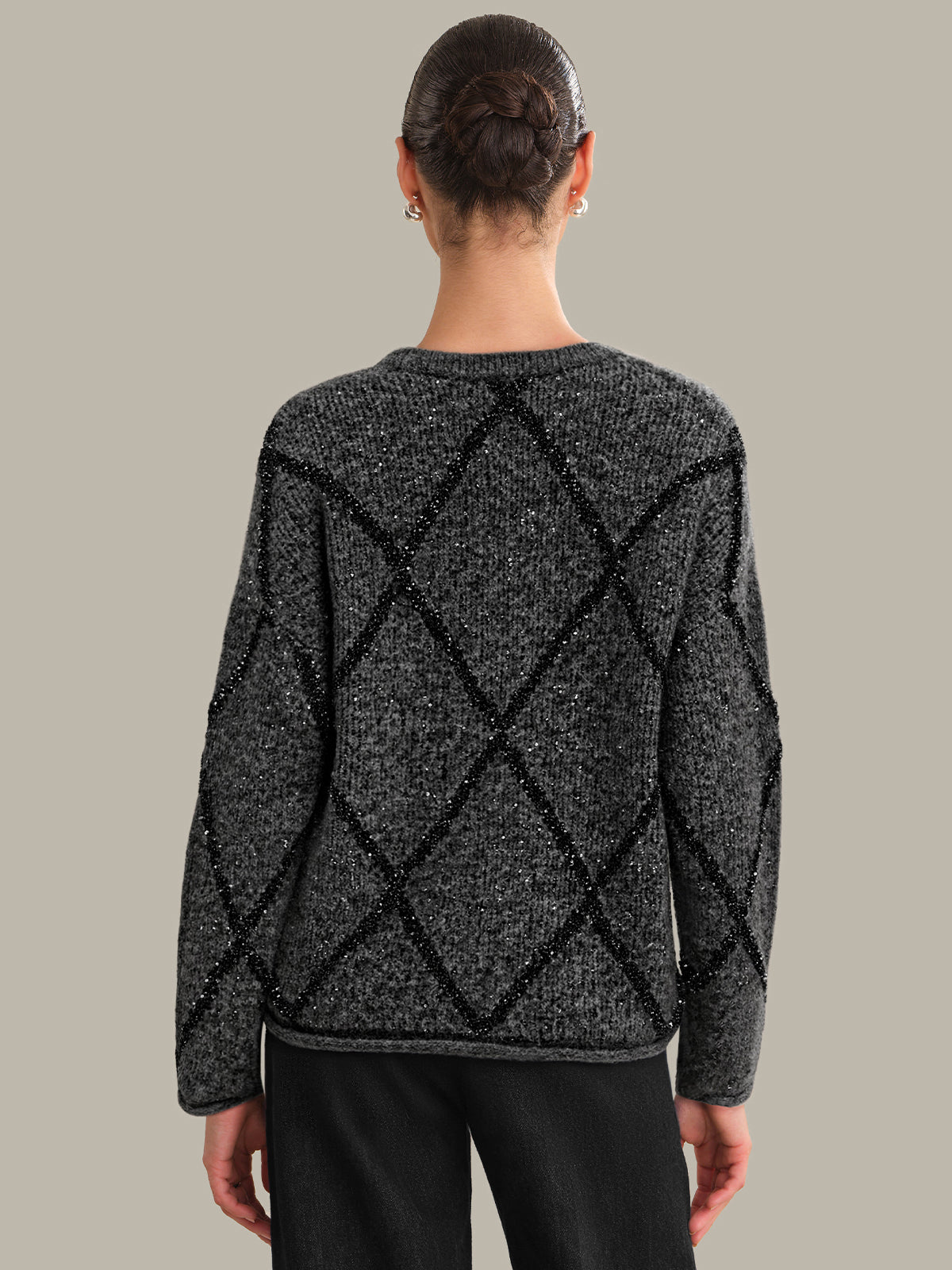 Person wearing a black and gray patterned sweater on a plain background