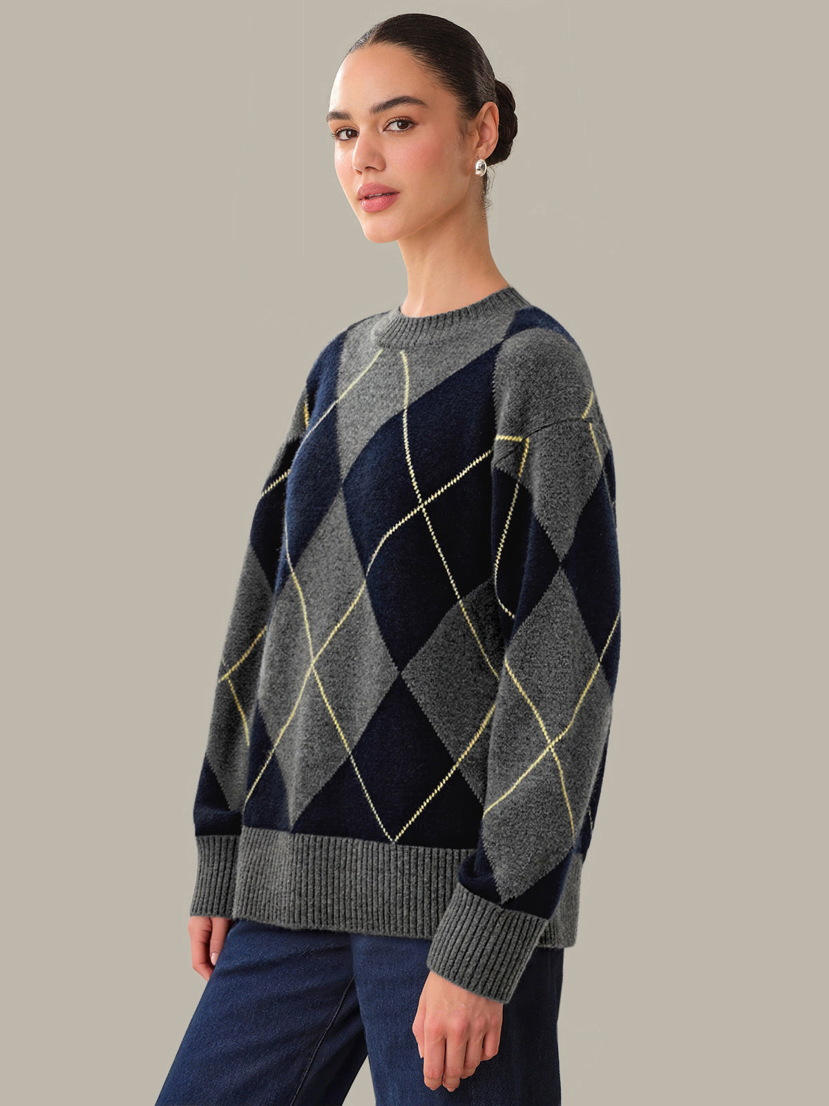 Woman wearing a black and gray argyle sweater against a plain background