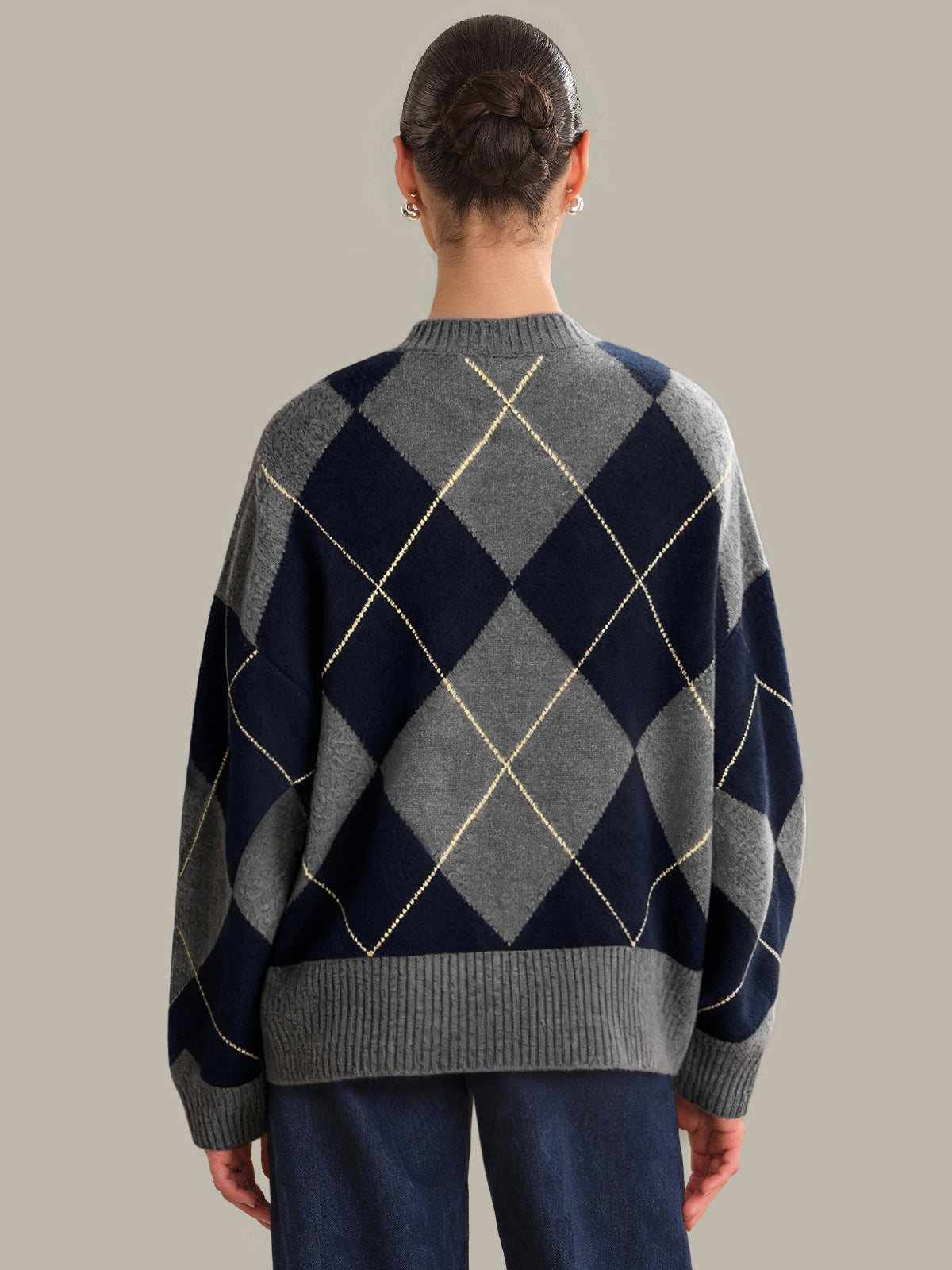 Person wearing a navy and gray argyle sweater on a plain background