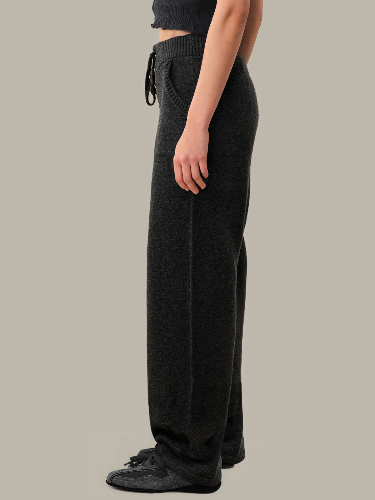 Person wearing dark gray pants on a plain background