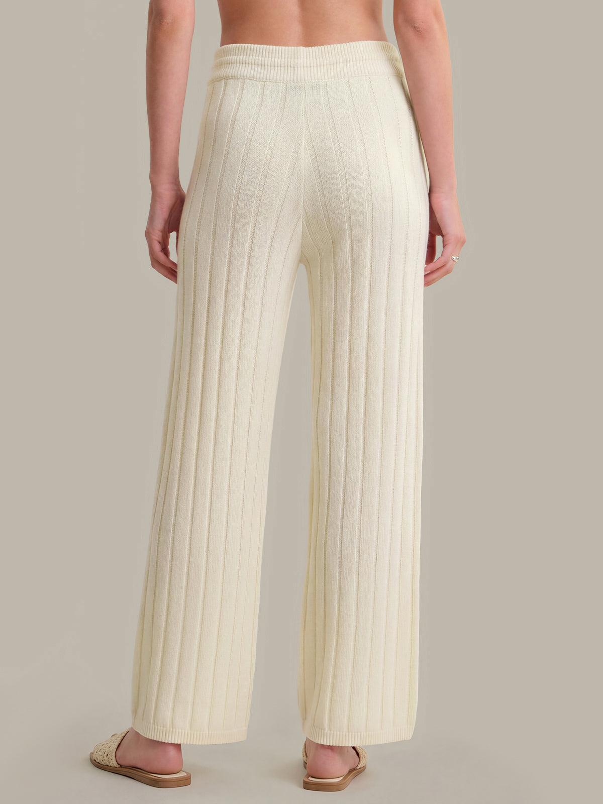 Person wearing cream ribbed knit pants on a neutral background