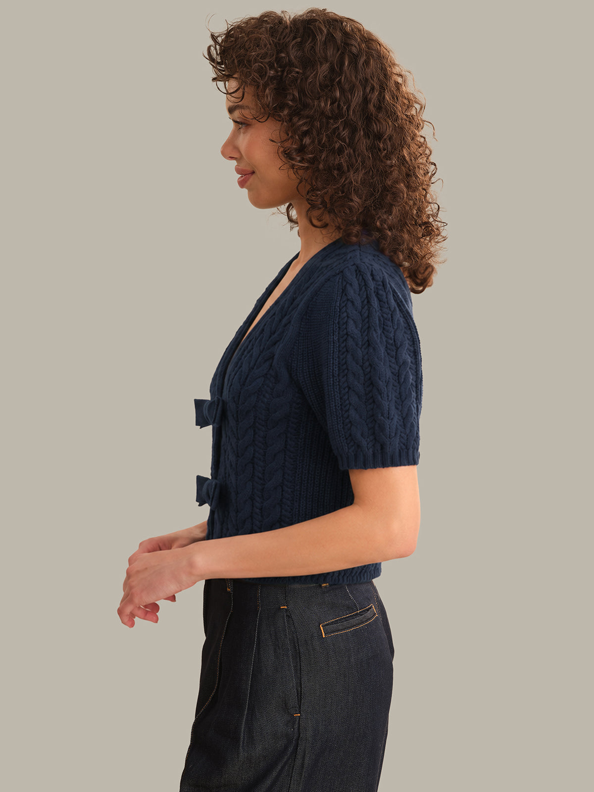 Woman wearing a navy blue cable knit cardigan against a plain background