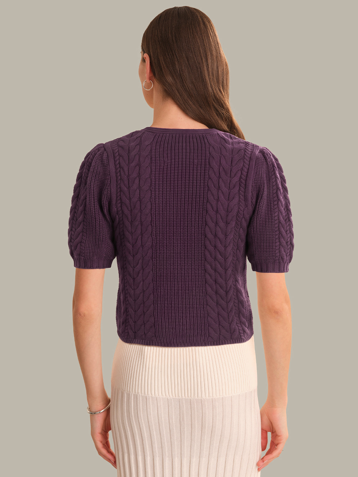 Woman wearing a purple knitted sweater against a plain background