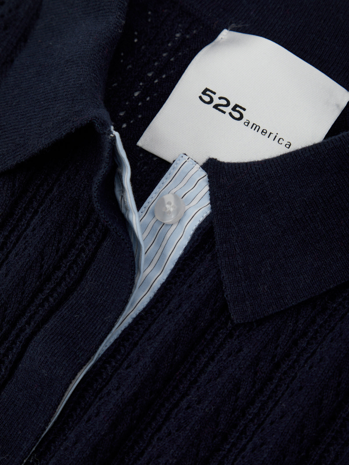 Close-up of a navy sweater with a brand tag displaying '525 America'.