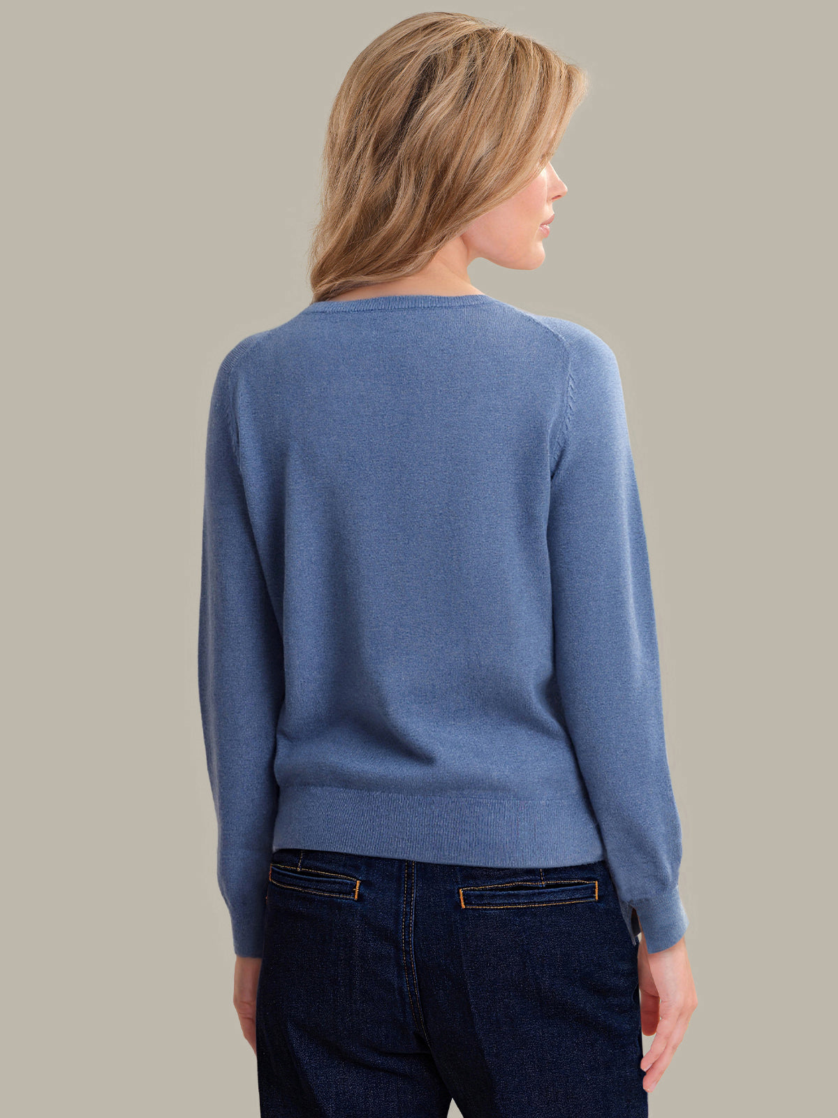 Woman wearing a blue sweater against a gray background