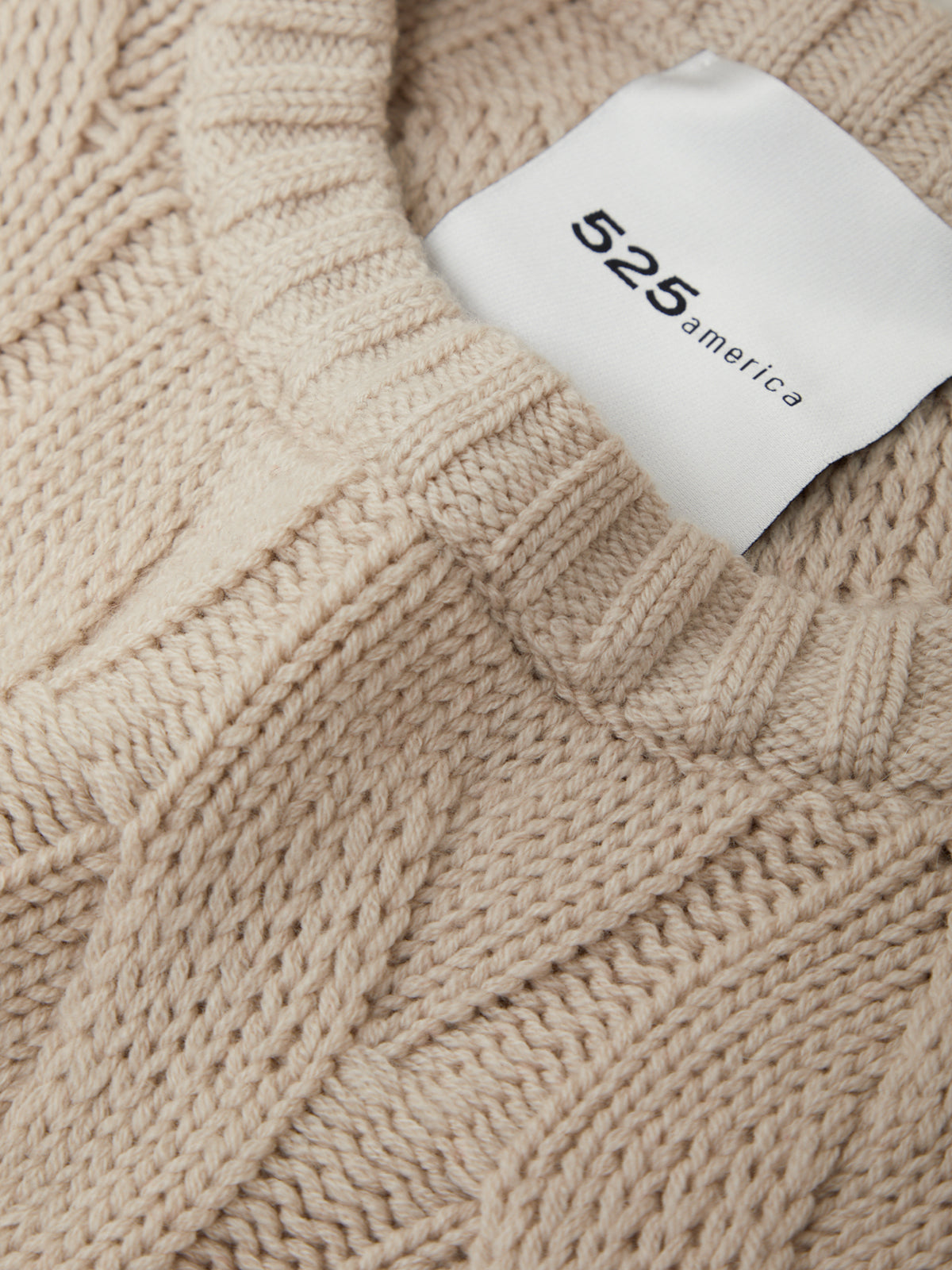 Close-up of a beige knitted sweater with a brand tag displaying '525 america'.
