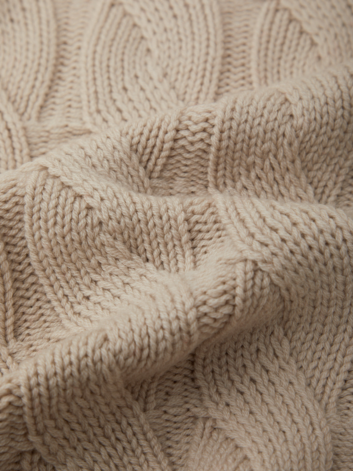 Close-up of a beige knitted fabric with a textured pattern