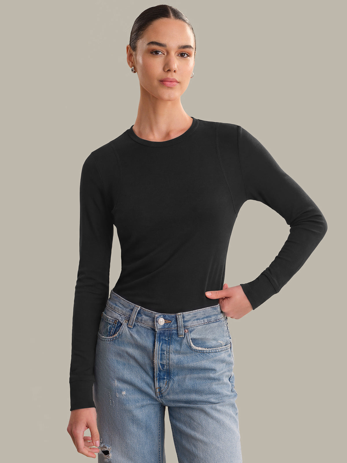 Person wearing a black long-sleeve shirt and blue jeans on a gray background