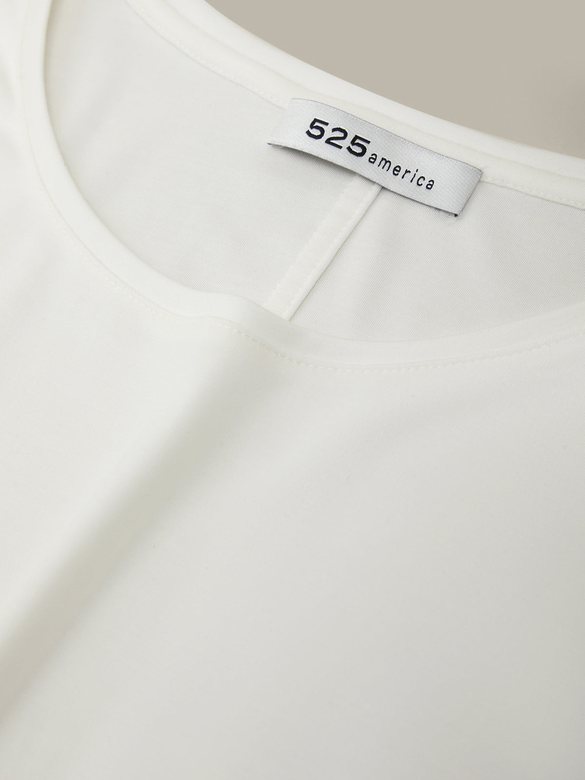 Close-up of a white garment with '525 america' label on a beige background