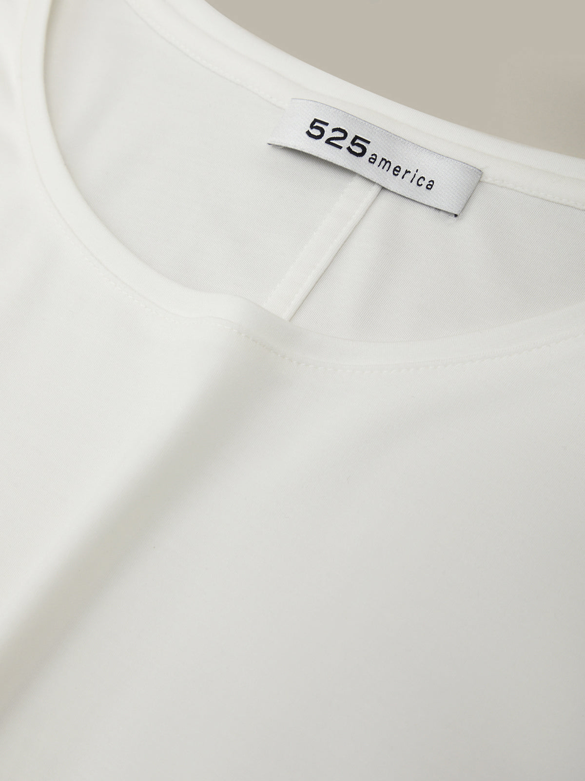 Close-up of a white shirt with '525 america' label on a beige background