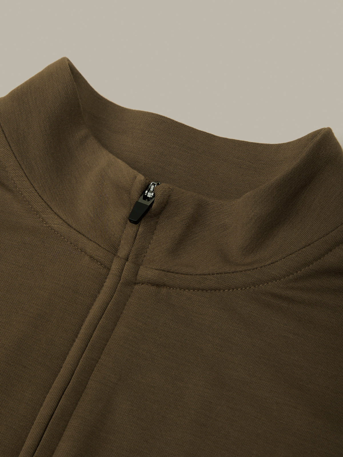 Close-up of a brown jacket with a zipper on a beige background
