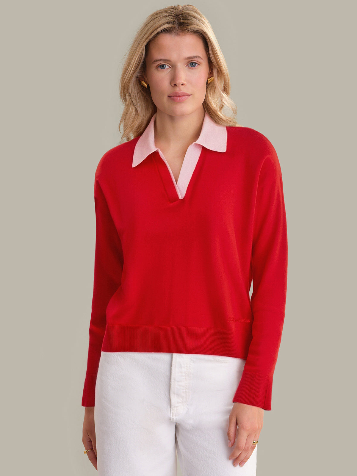 Woman wearing a red sweater with a pink collar against a neutral background