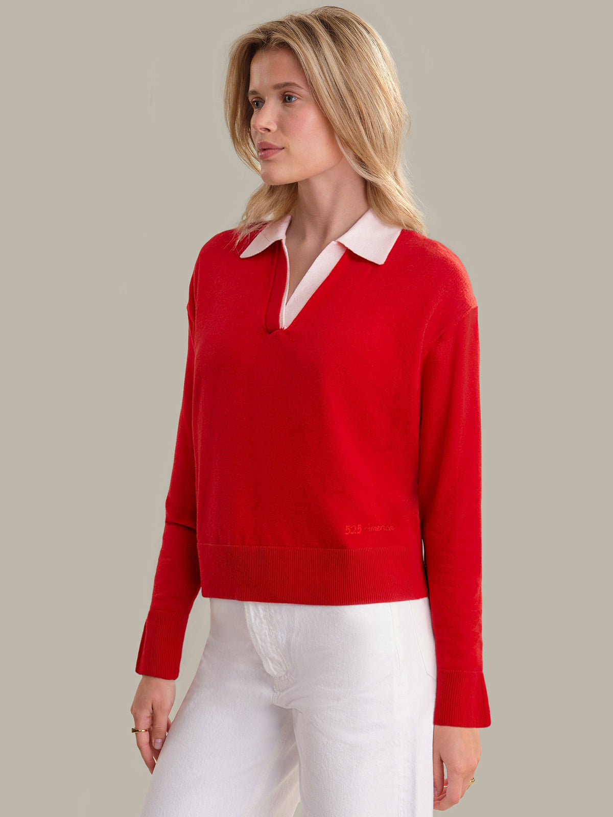 Woman wearing a red sweater with a white collar against a plain background