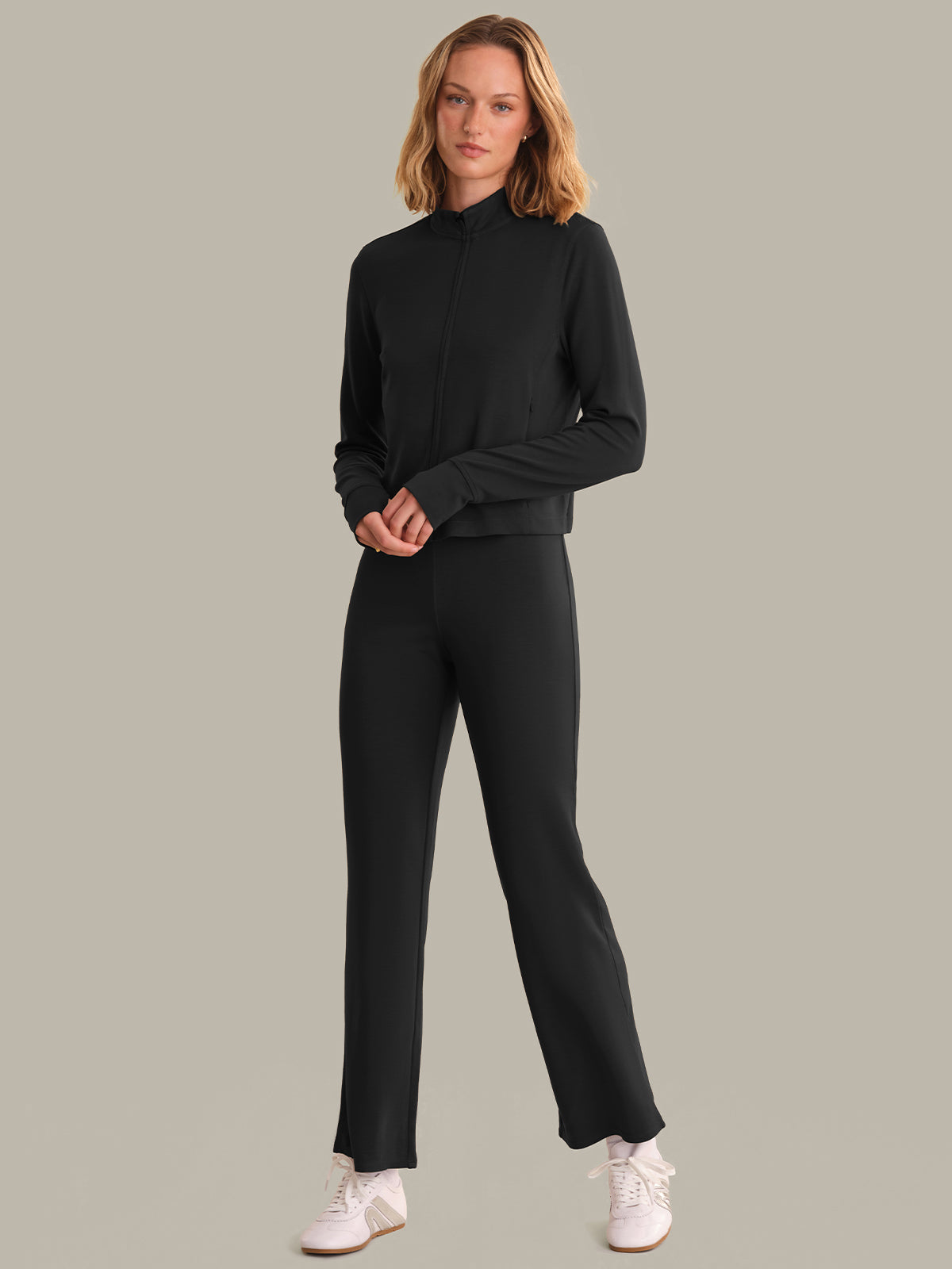 Woman wearing a black outfit with white shoes on a gray background