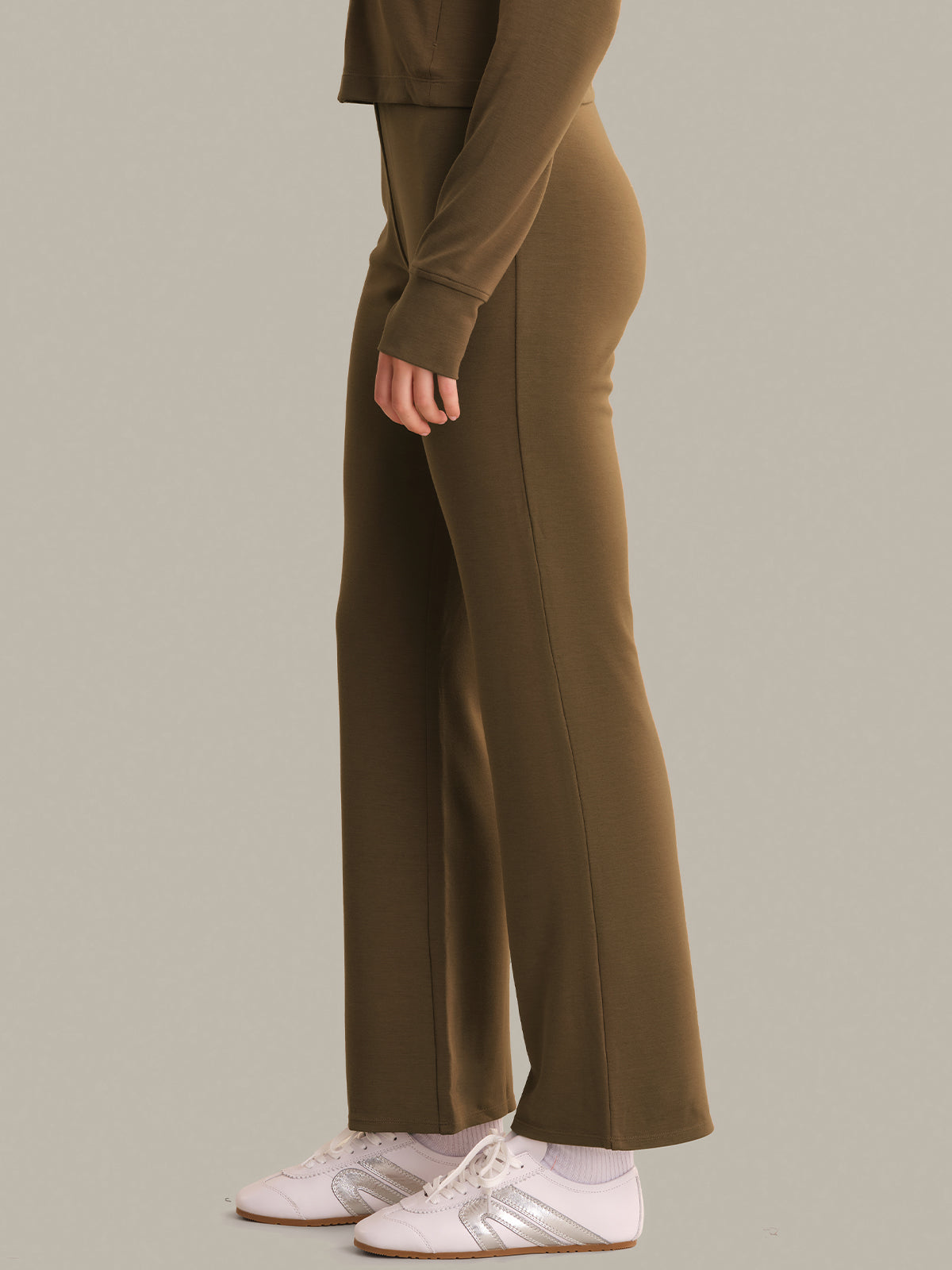 Person wearing a brown outfit with wide-leg pants on a plain background