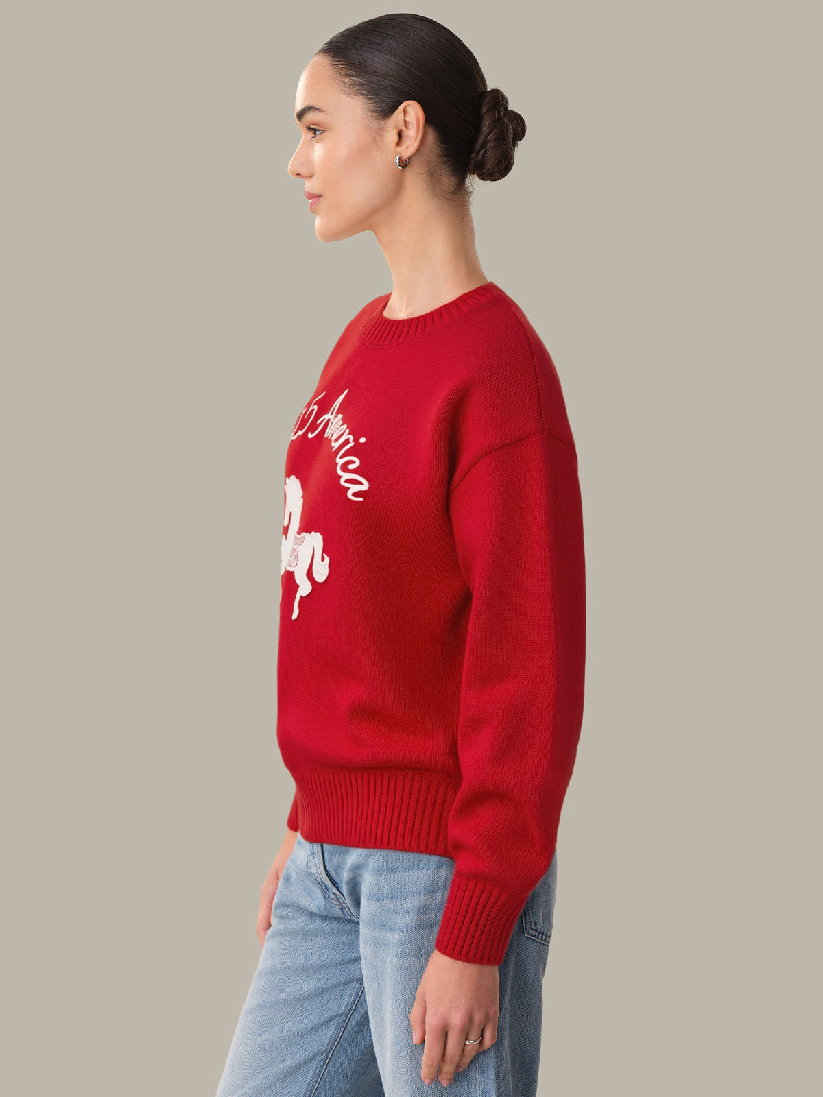Person wearing a red sweater with a graphic design on a plain background