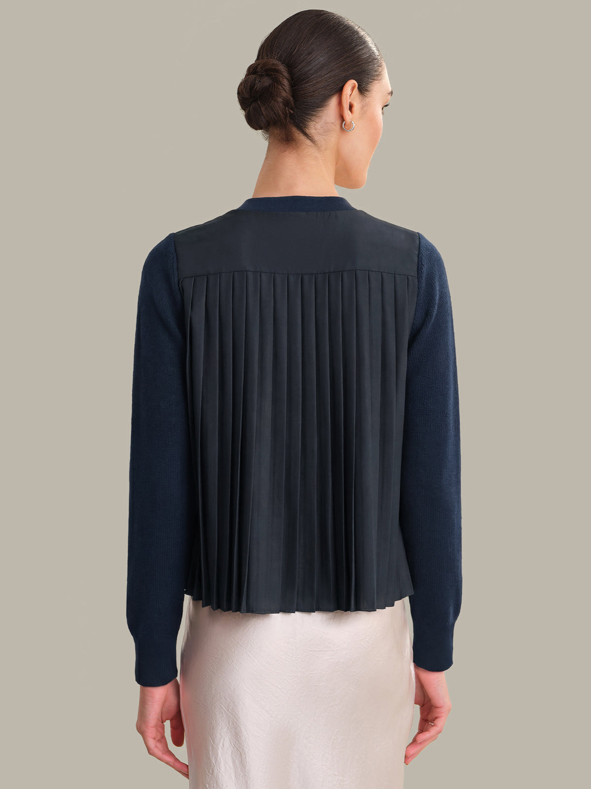 Person wearing a navy pleated blouse against a neutral background