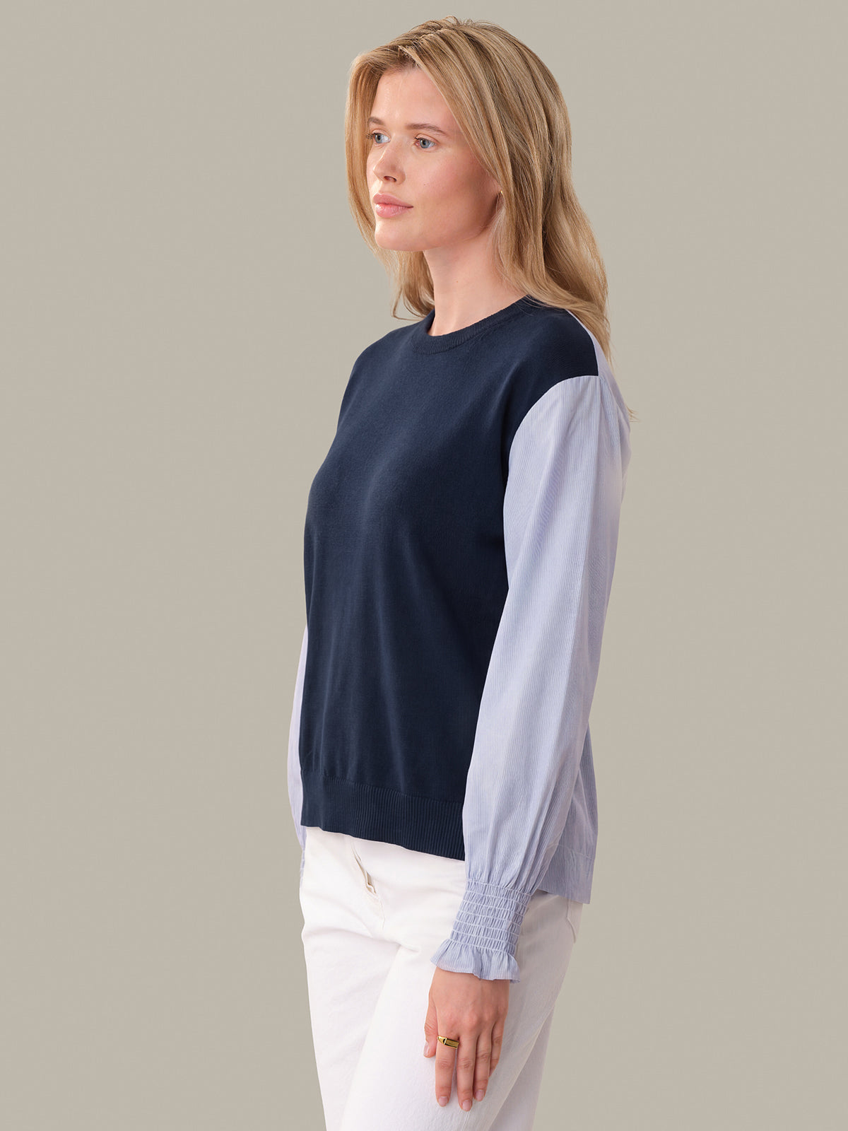 Woman wearing a navy and light blue color-blocked sweater against a plain background