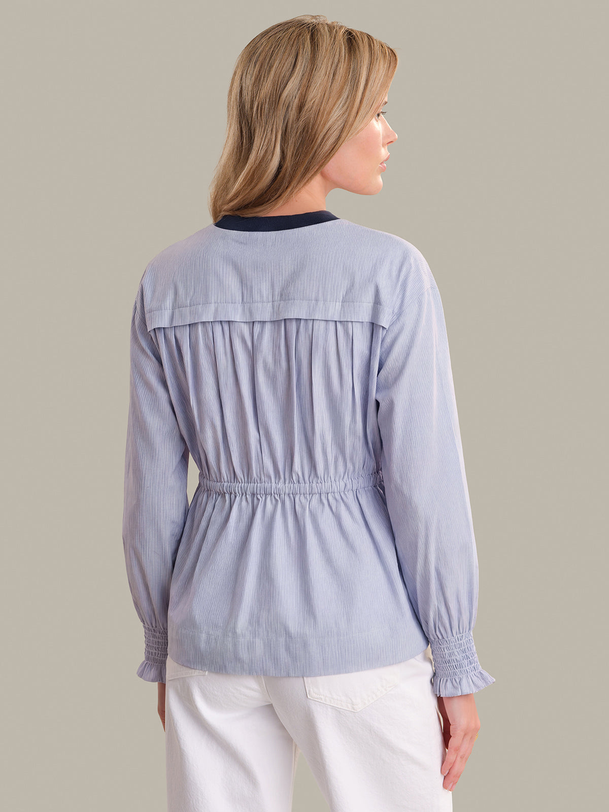 Woman wearing a light blue jacket with a neutral background