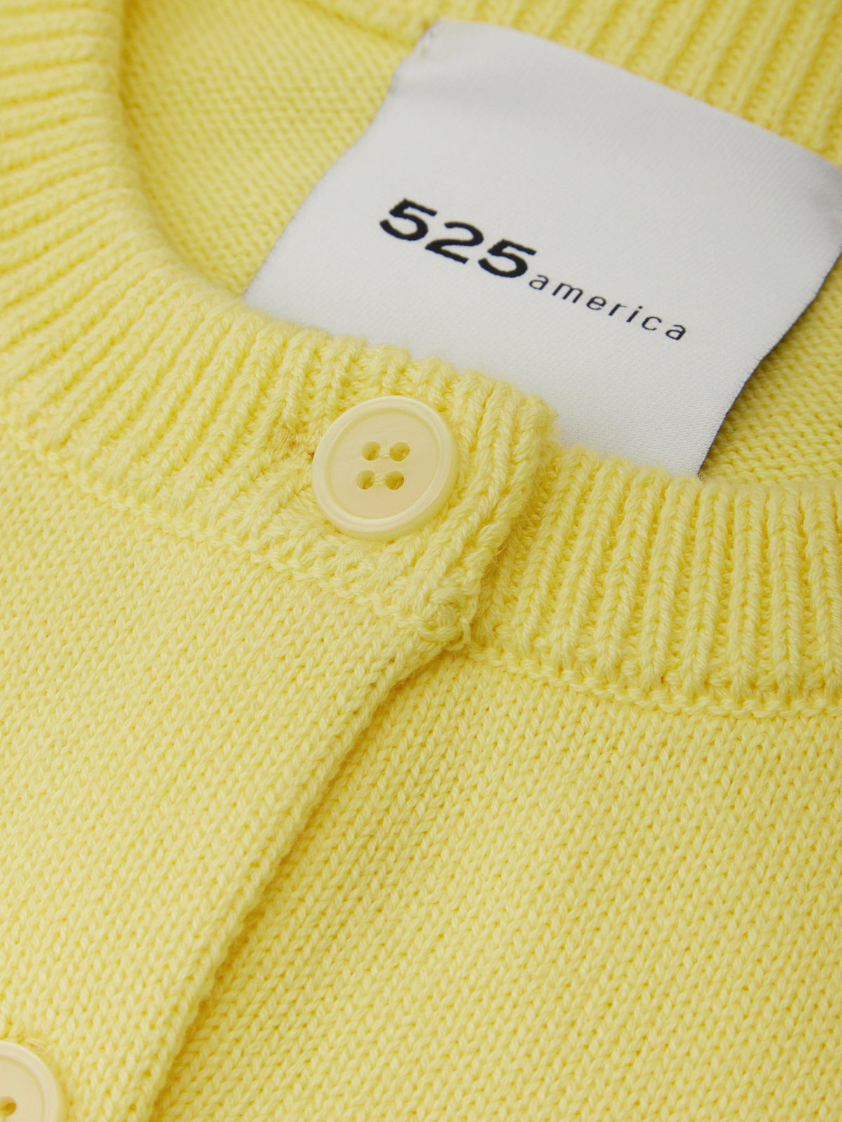 Yellow knitted garment with a label displaying '525 america' on a white background