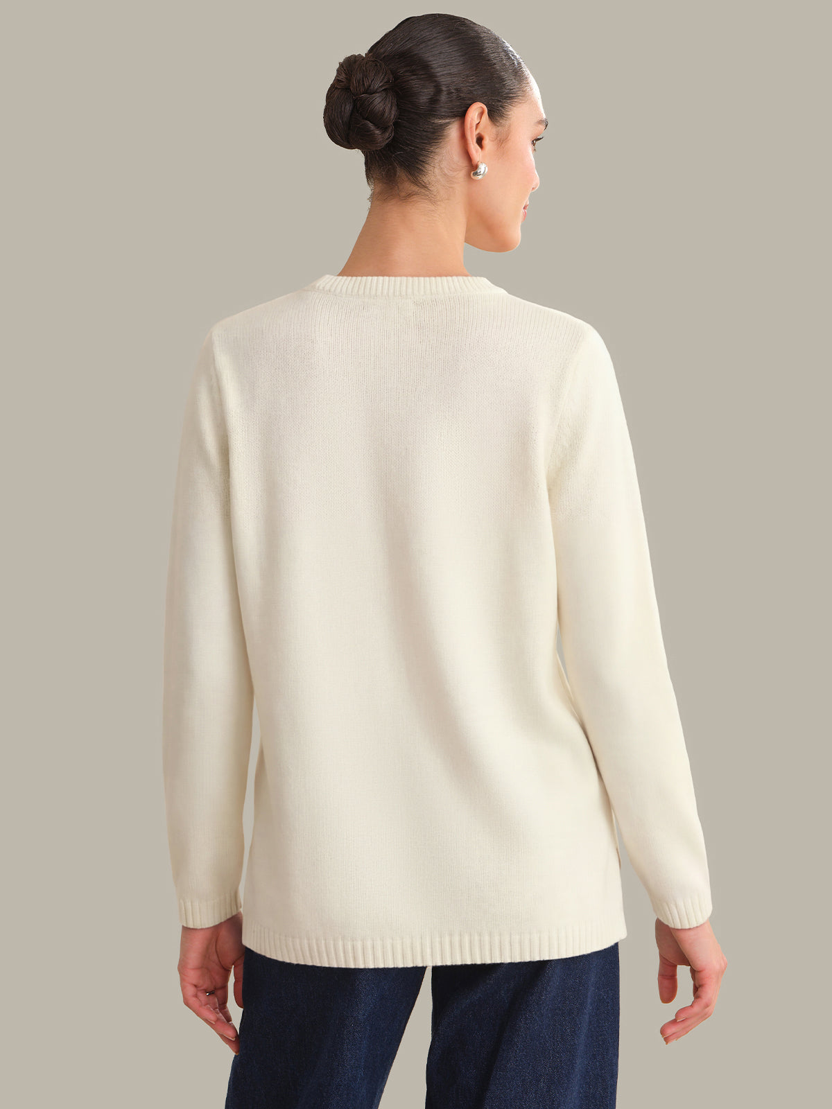 Woman wearing a cream sweater against a plain background