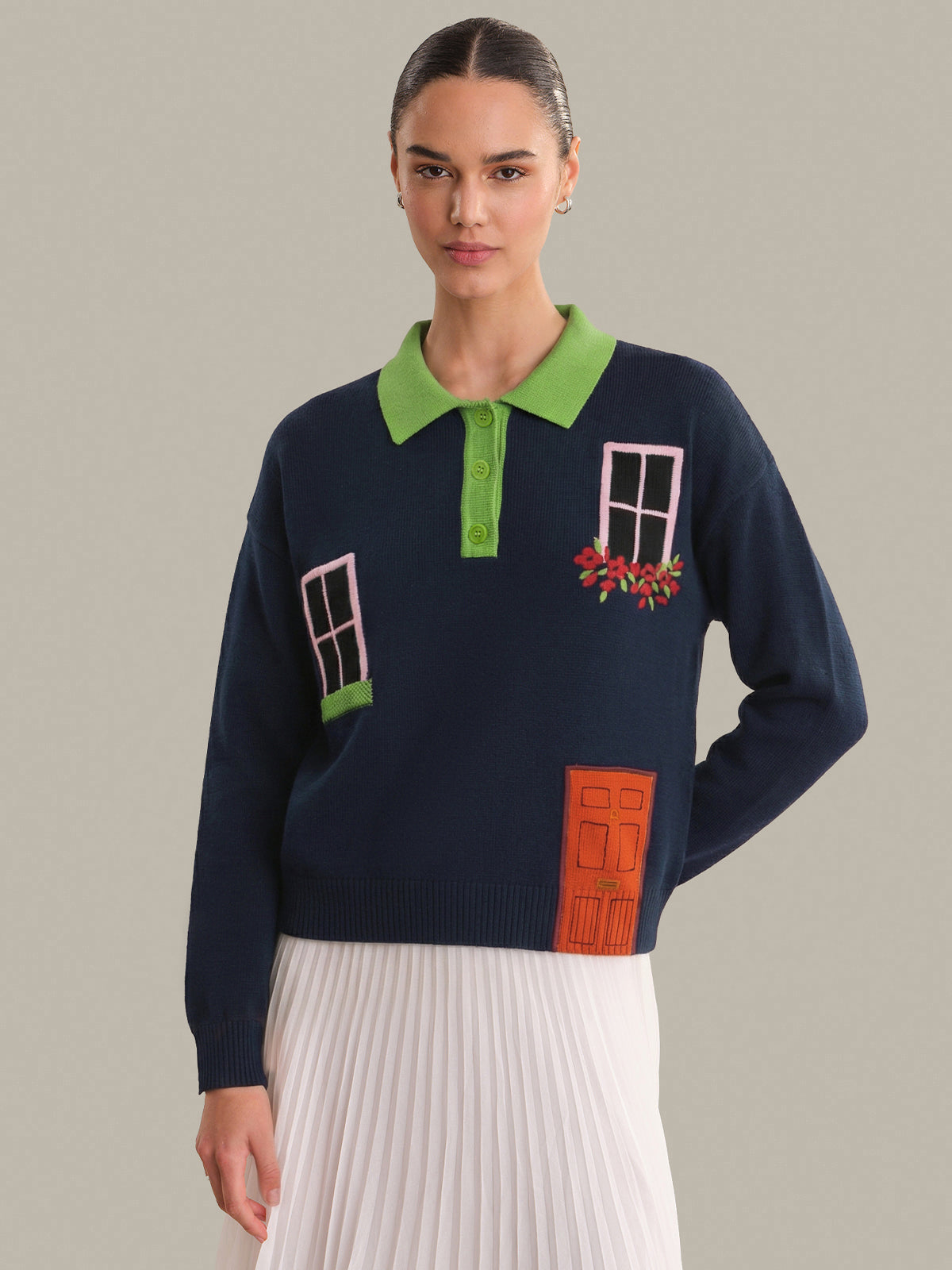 Woman wearing a navy sweater with window and door designs on a plain background