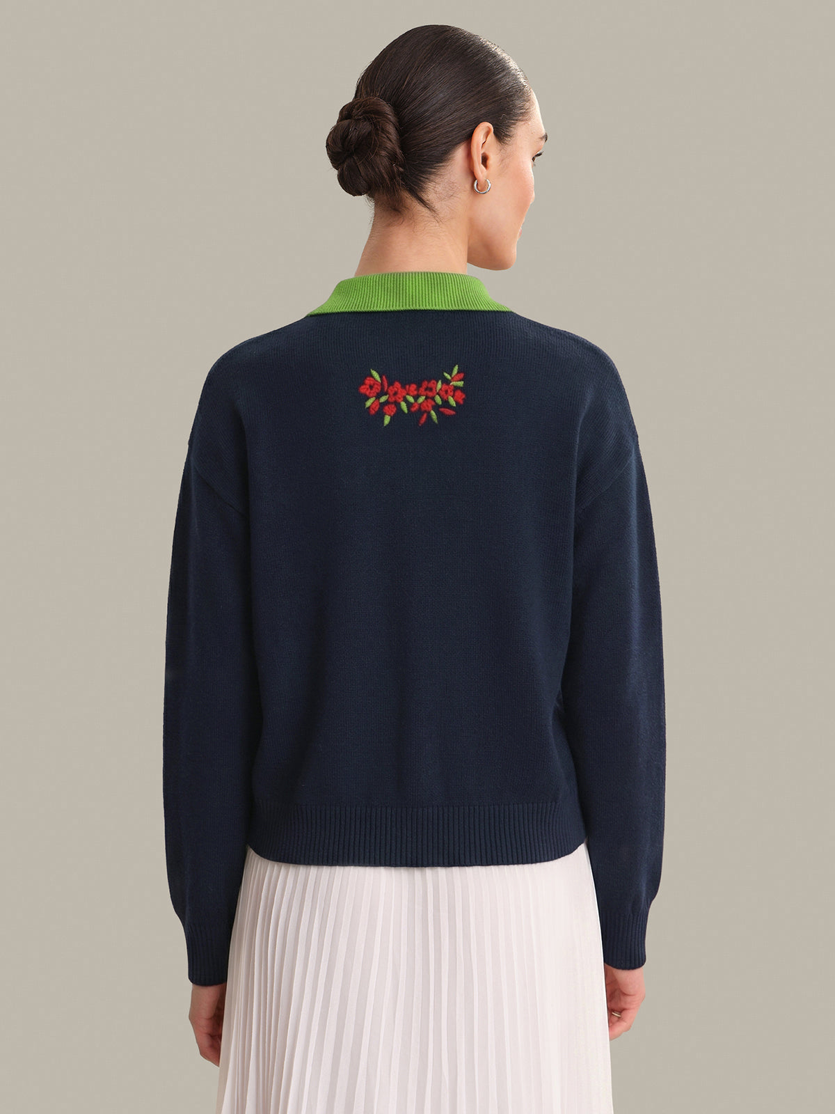 Navy sweater with green collar and floral embroidery on a plain background