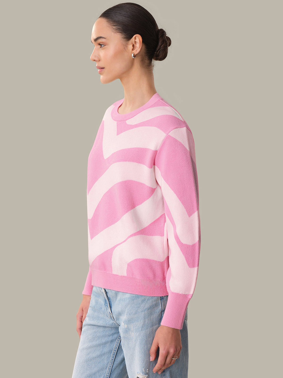 Person wearing a pink and white patterned sweater on a gray background