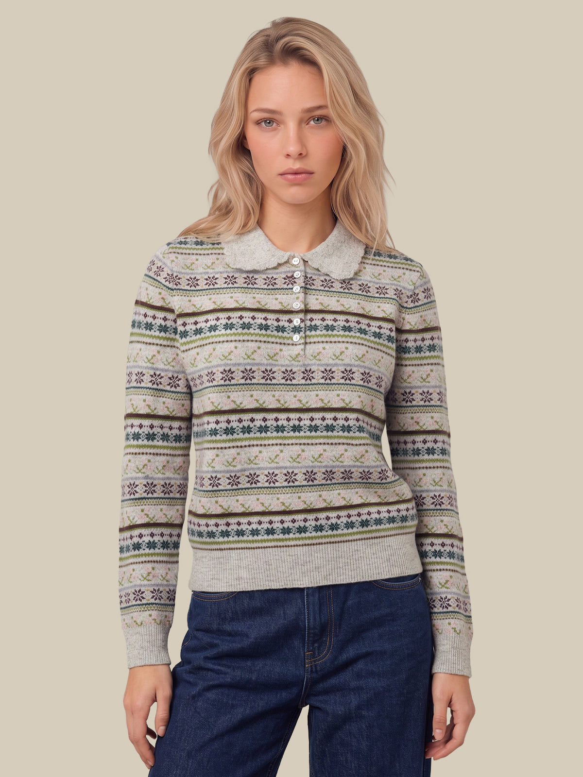 A woman wearing a long-sleeve knit polo sweater with a beige, gray, and blue Fair Isle pattern, paired with dark blue jeans, set against a solid beige background.