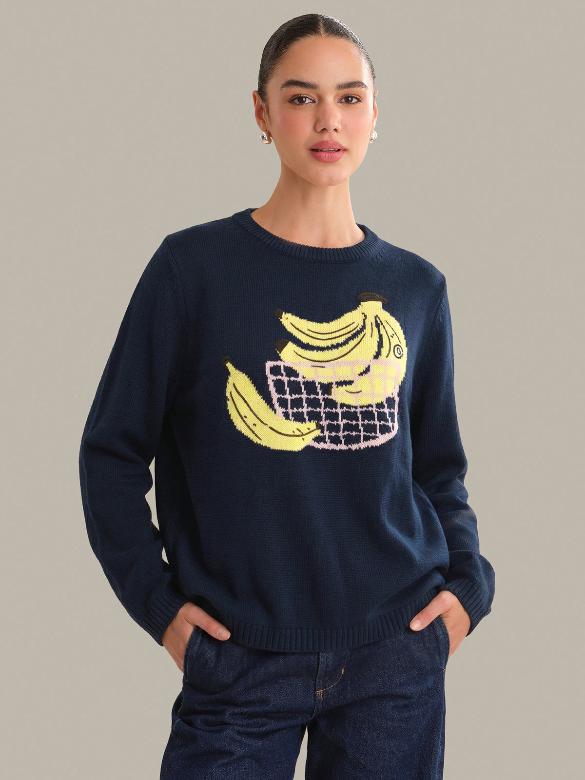 Person wearing a navy sweater with a banana design on a plain background