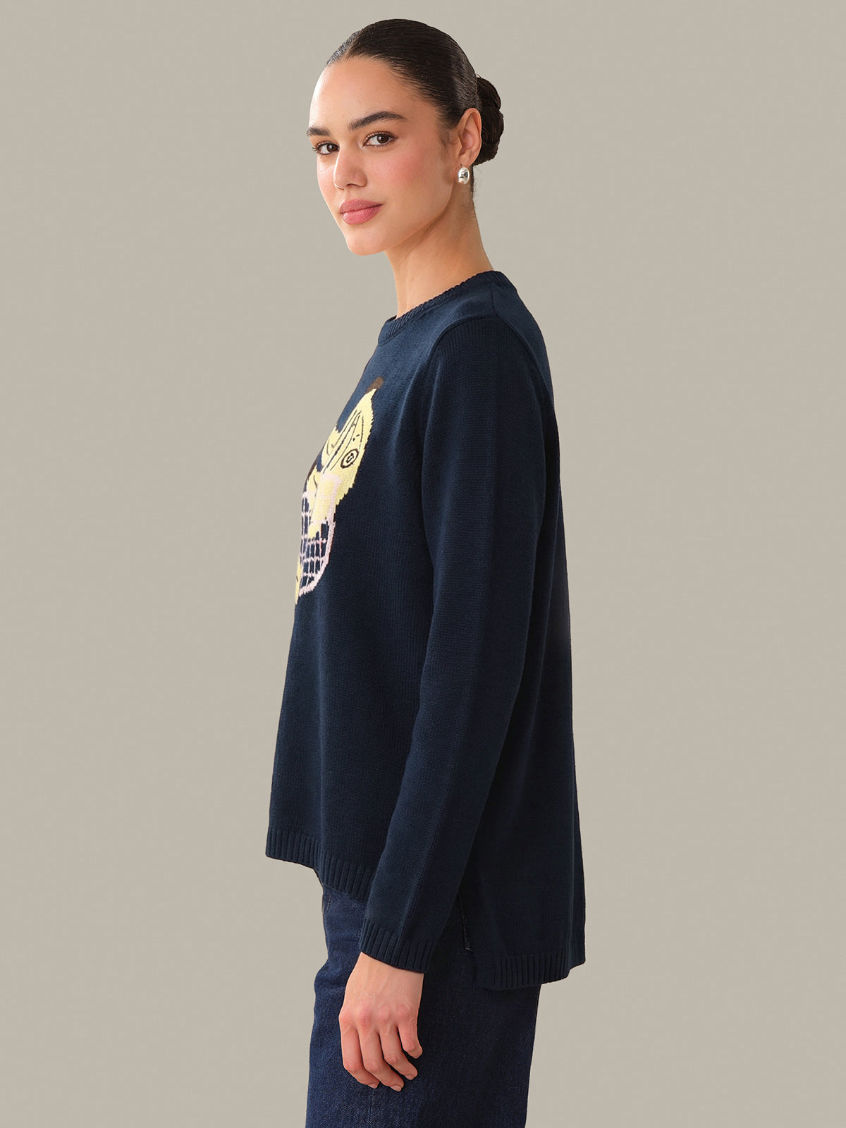 Person wearing a navy sweater with a yellow graphic on a plain background