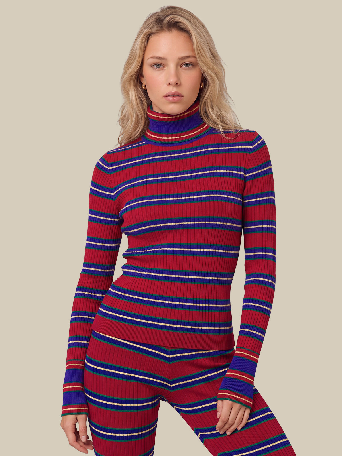 A woman modeling a ribbed knit matching set consisting of a long-sleeve turtleneck top and high-waisted leggings, featuring horizontal stripes in red, blue, and white, against a solid beige background.