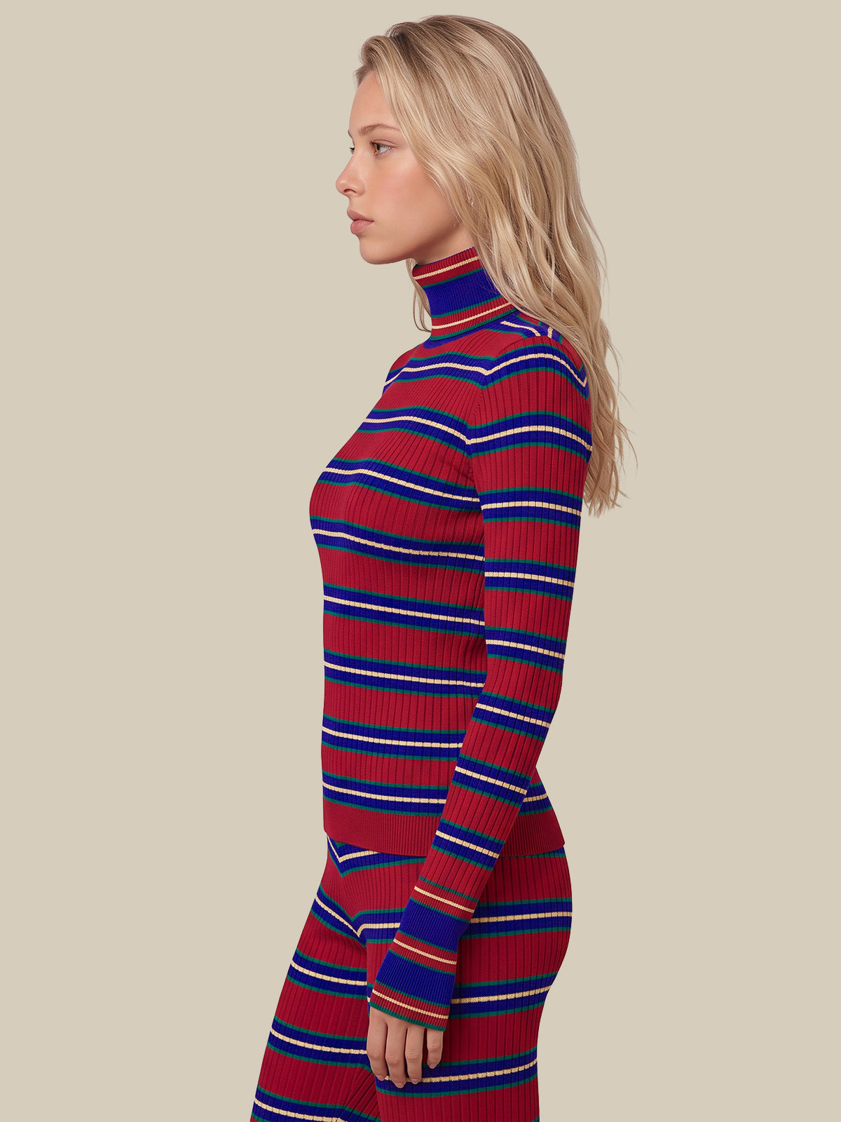 A woman in profile wearing a ribbed turtleneck sweater dress with horizontal red, royal blue, and white stripes, set against a solid beige background.