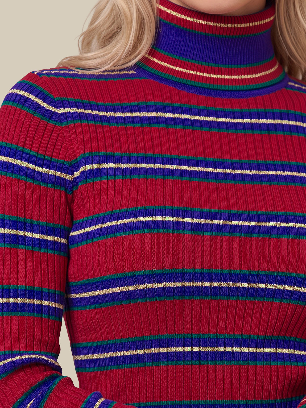A close-up of a ribbed knit turtleneck sweater with horizontal stripes in red, blue, green, and cream, worn by a model.