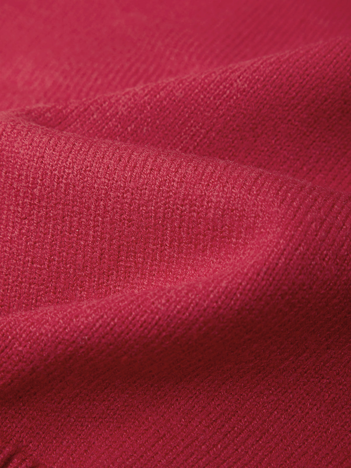 A close-up of textured knit fabric in a rich magenta pink color, showing the detailed ribbed weave and soft folds.