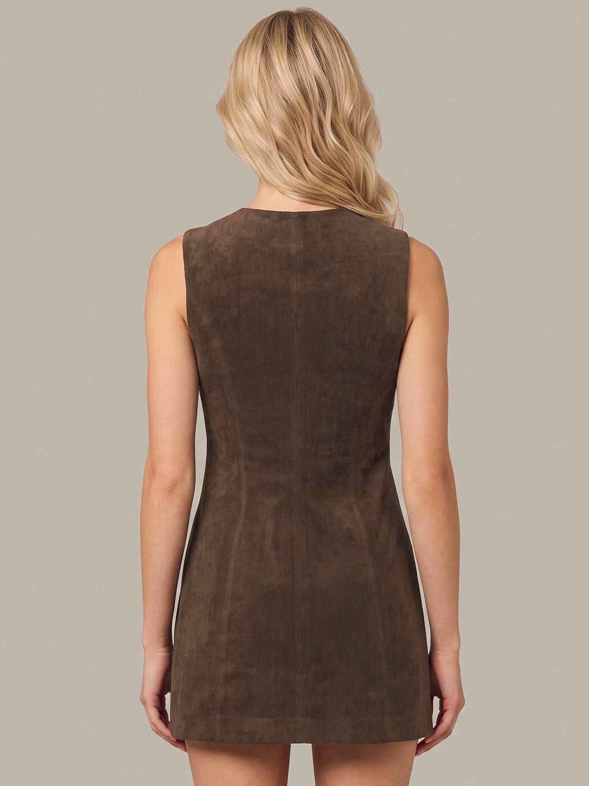 A woman viewed from the back wearing a sleeveless brown dress with a textured suede-like finish, set against a solid light gray background.